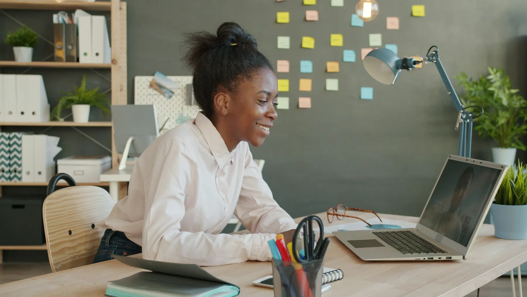 Emprendedora sonriendo mientras trabaja con su laptop en un espacio de trabajo luminoso